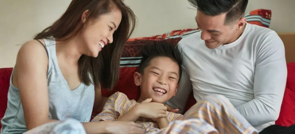 A cheerful family on a sofa, embodying a modern Filipino lifestyle for all life stages in a PHINMA Properties community.