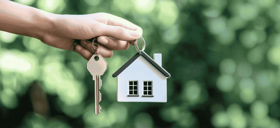 A hand holds a house-shaped keychain and a silver key, representing the goal of a condo buying guide for OFWs in Bacolod.