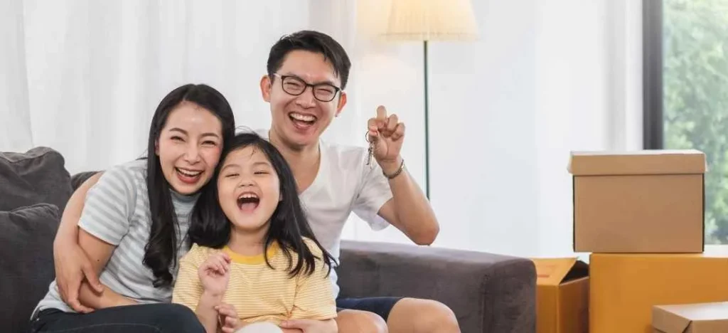 Smiling parents and daughter with moving boxes, celebrating buying a future proof condo in the Philippines at Metrotowne.